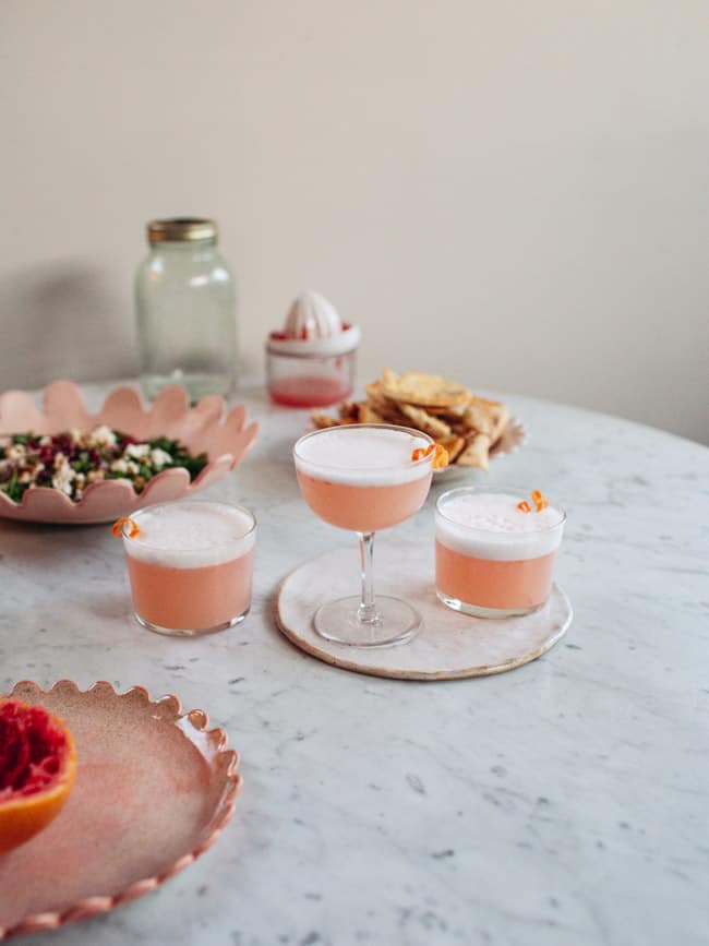Three glasses of a pink cocktail with foamy tops.