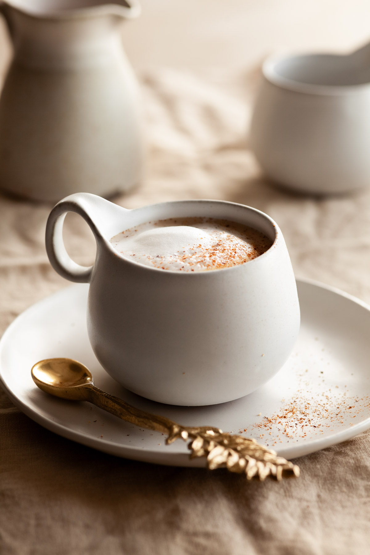 A white mug filled with a light orange drink and whipped cream.
