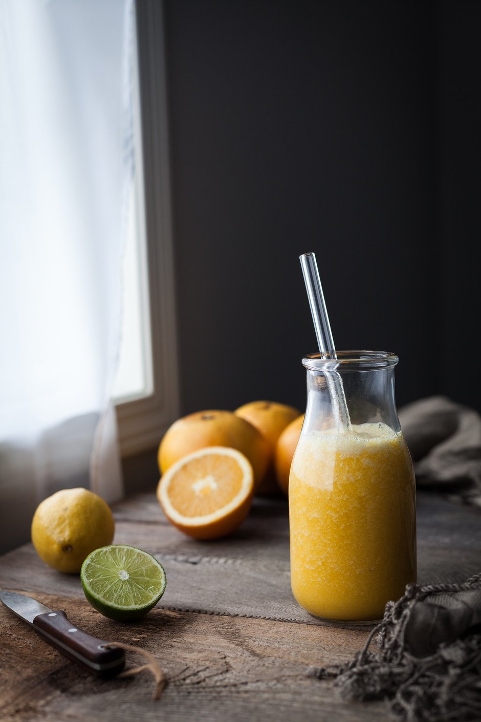 A small bottle with a citrus drink and a straw.