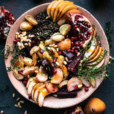 Lentil salad with beets, shallots, pomegranate, and pears in a large pink bowl.
