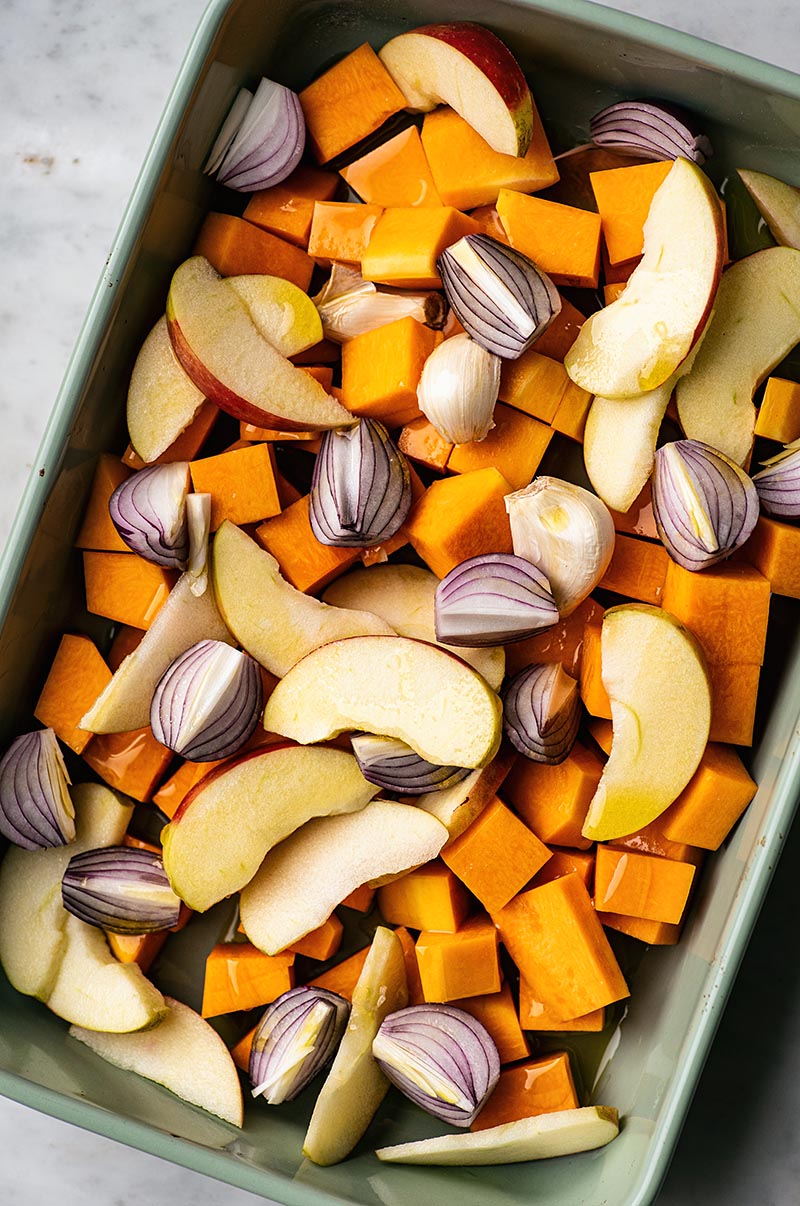 Tray with butternut squash, red onion, apples, and garlic before roasting.