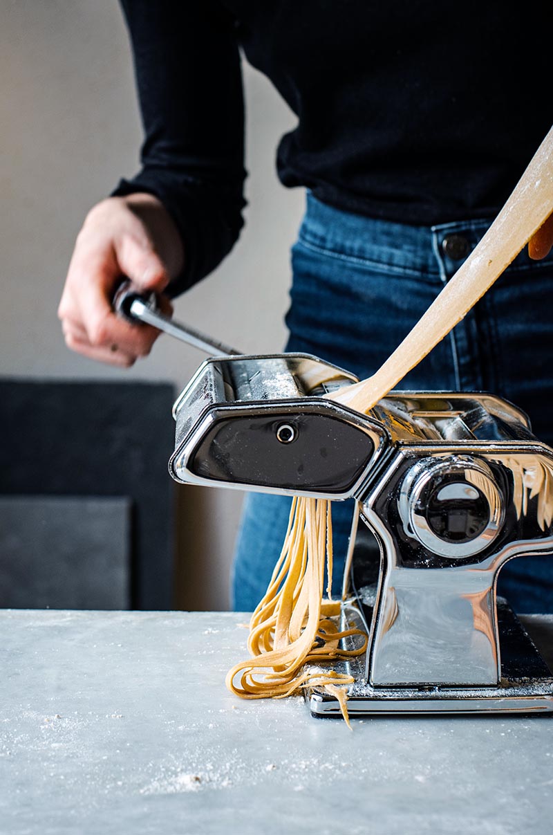 Woman making kamut pasta with a pasta machine.
