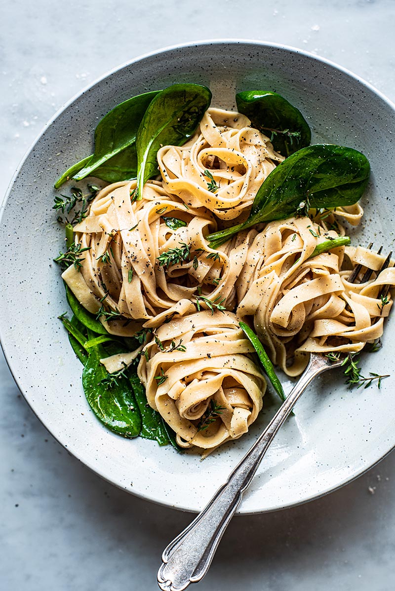 Tagliatelle with spinach and thyme in shallow bowl.