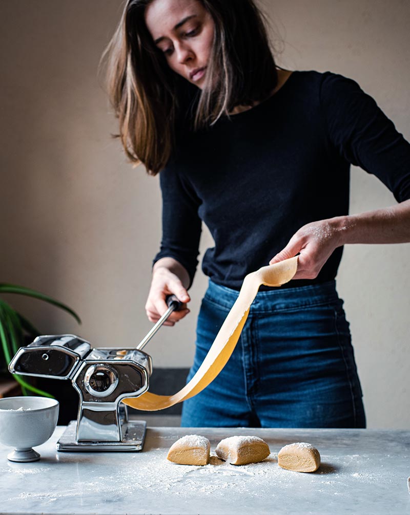 Woman making kamut pasta with a pasta machine.