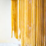 Kamut pasta cut into tagliatelle drying on a wooden wrack.