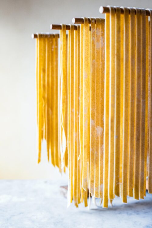 Kamut pasta cut into tagliatelle drying on a wooden wrack.