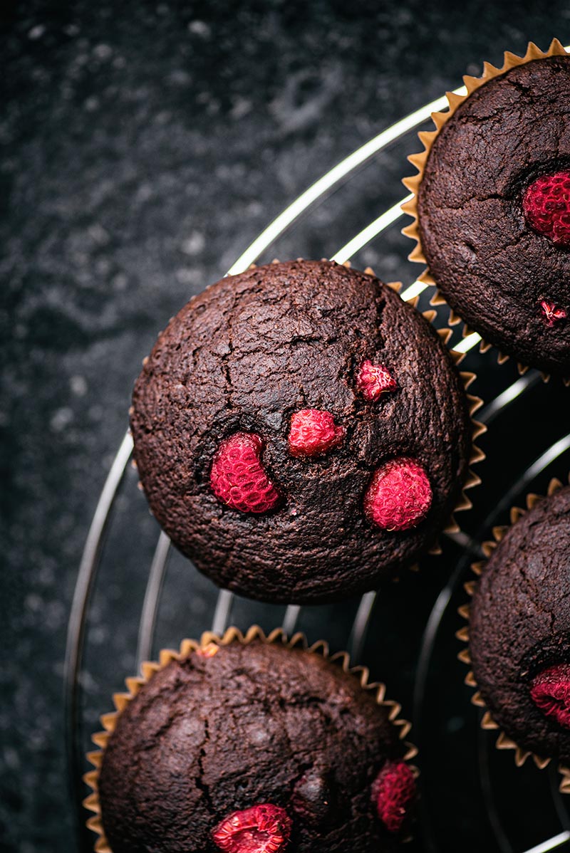 Raspberry chocolate muffins on a cooling rack.