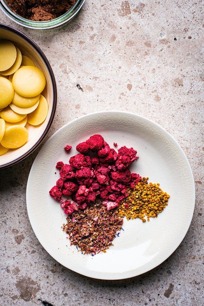 Small bowl with dried raspberries, bee pollen, and mixed spices and dried flowers, top down view.