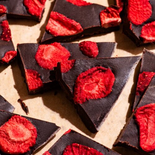Several pieces of chocolate broken into pieces, topped with freeze-dried strawberries.