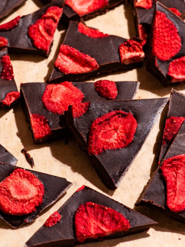 Several pieces of chocolate broken into pieces, topped with freeze-dried strawberries.