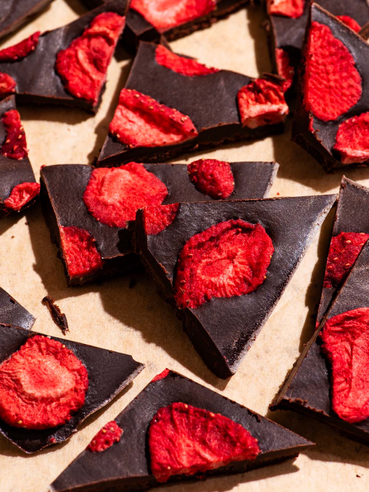 Several pieces of chocolate broken into pieces, topped with freeze-dried strawberries.
