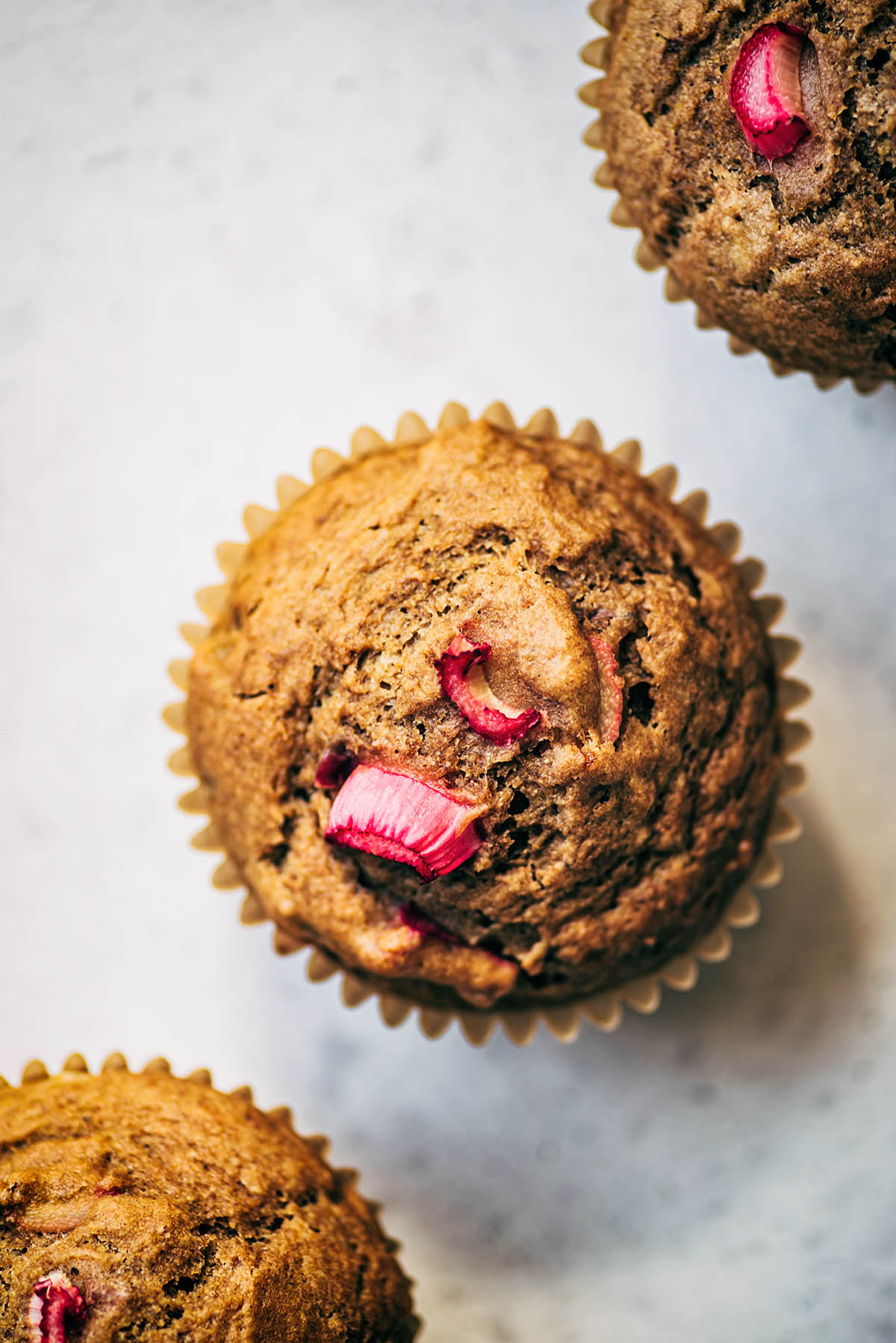 Three muffins in a diagonal row, topped with rhubarb.