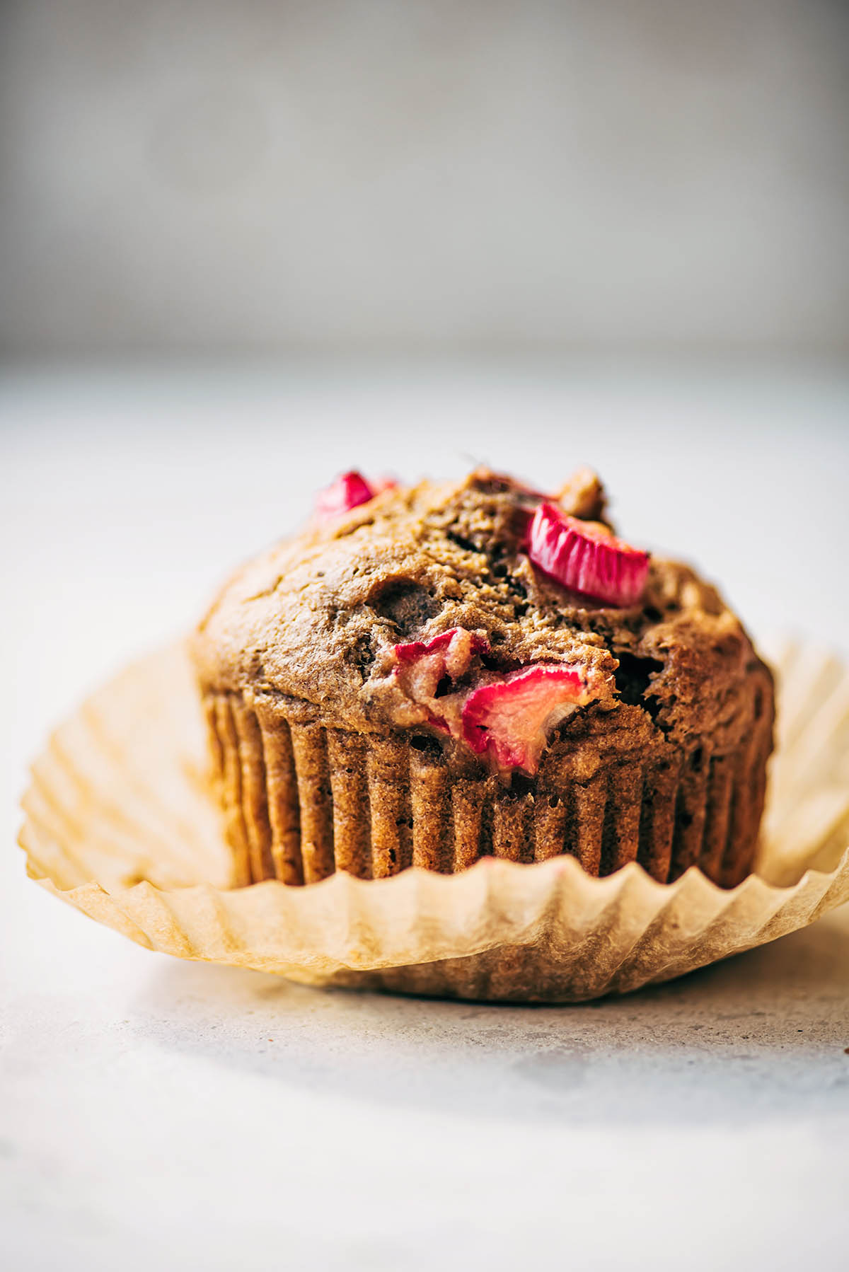 Muffin topped with rhubarb in a paper liner.