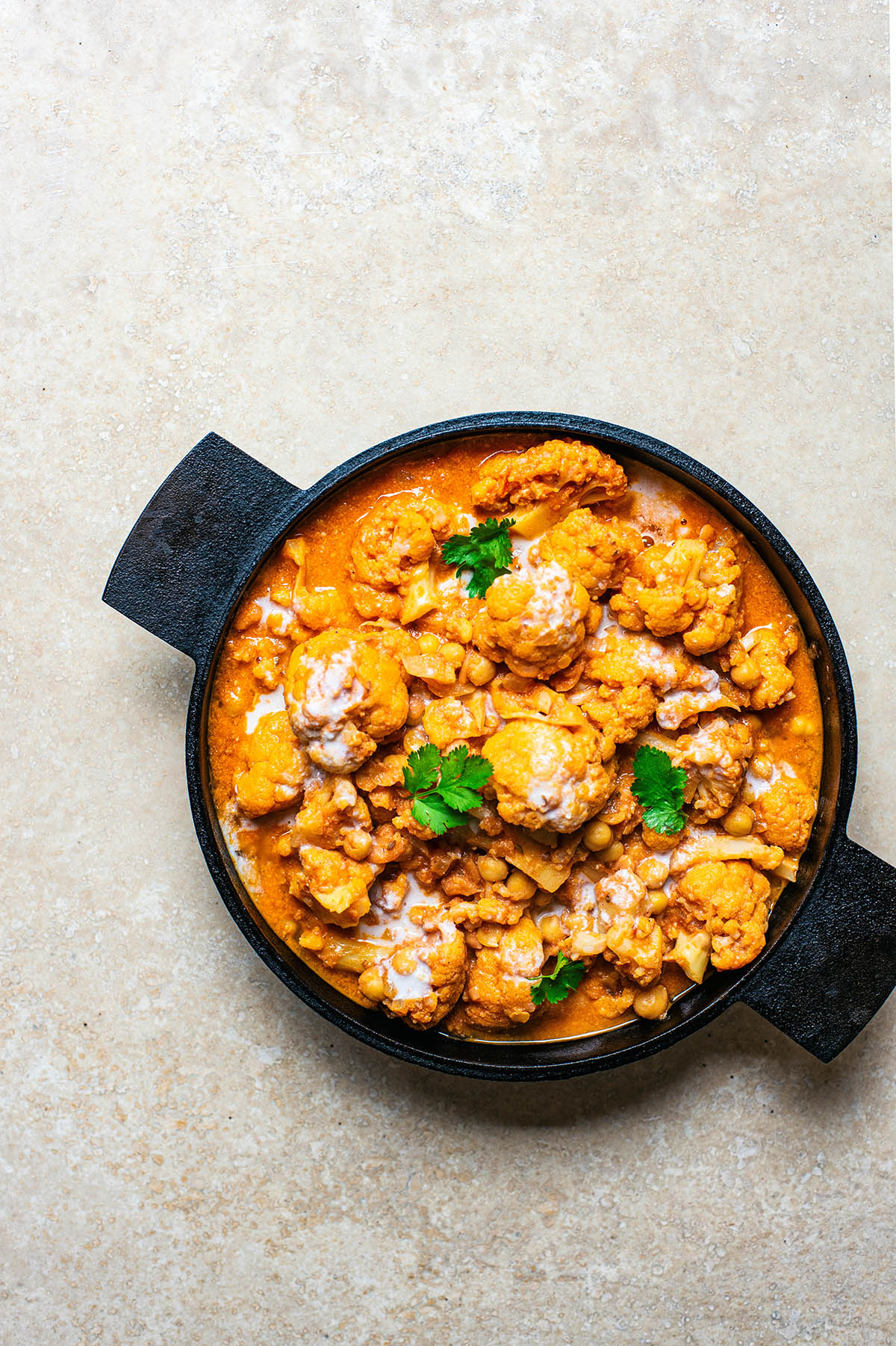 Cauliflower curry in a black pan with cilantro.