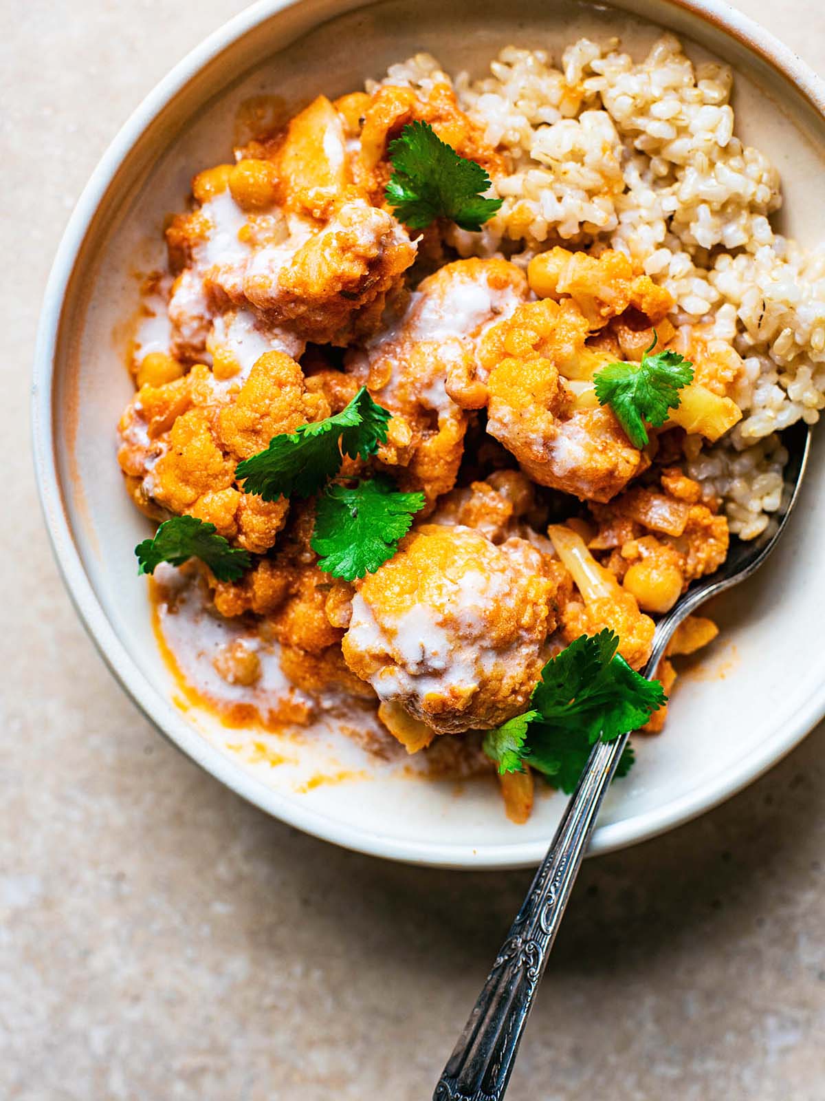 Cauliflower curry with rice in a bowl, topped with fresh coriander.