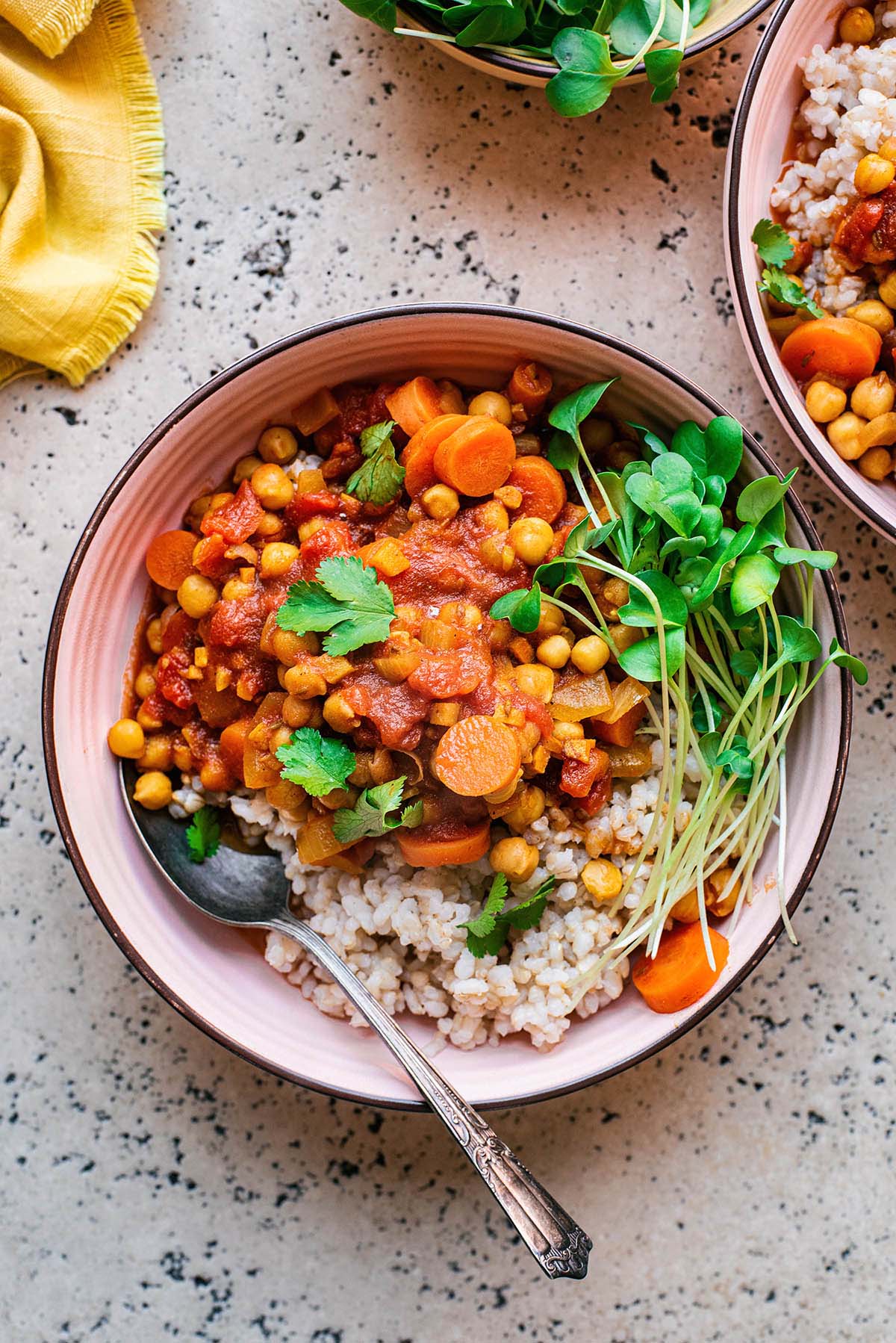 Bowls of chickpea stew with rice on a stone background.