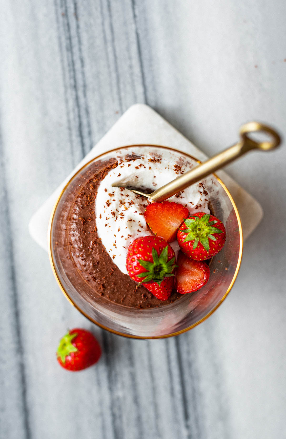 Close up of chocolate mousse with whipped cream and strawberries.