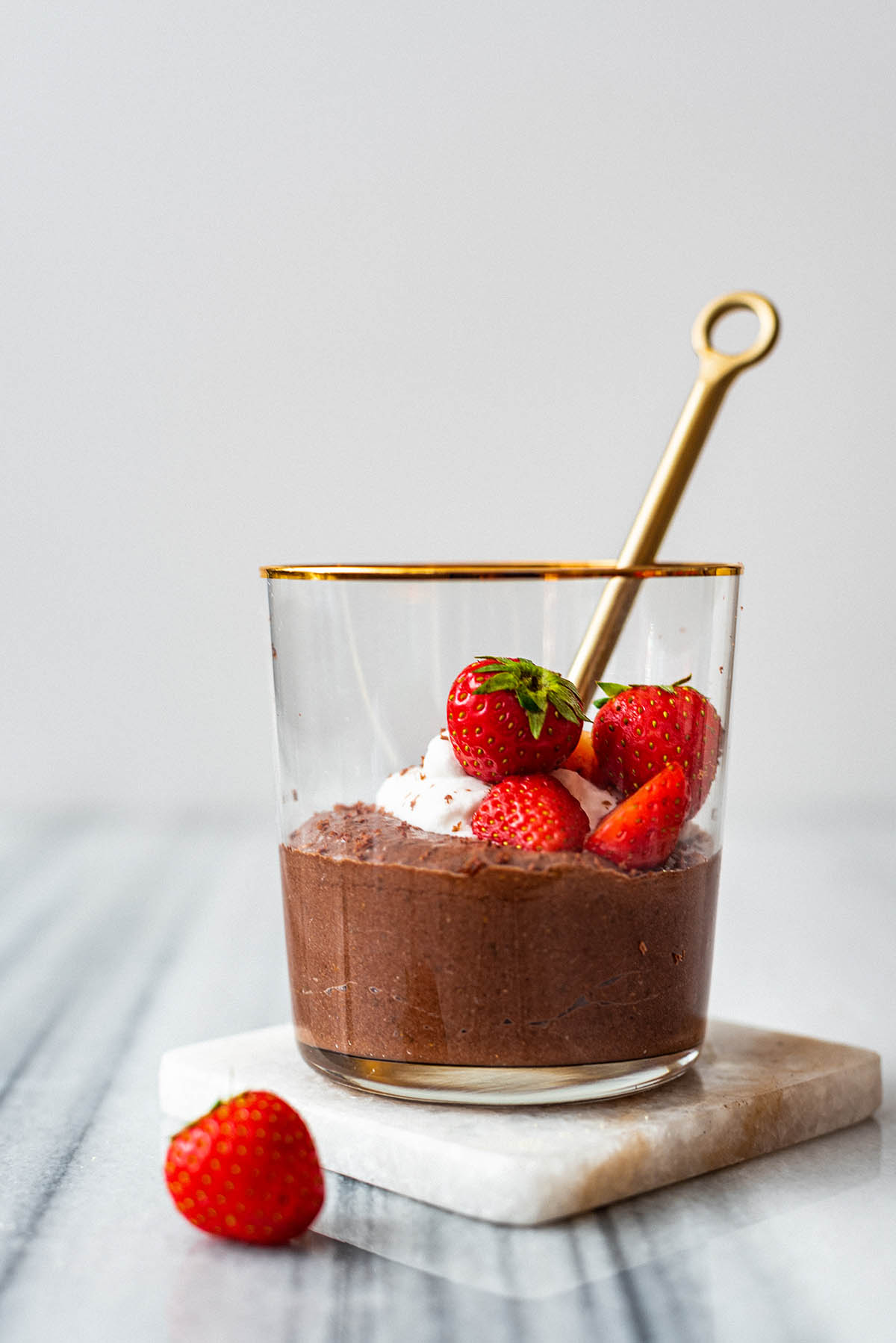 Chocolate chia mousse in a glass with whipped cream and strawberries.
