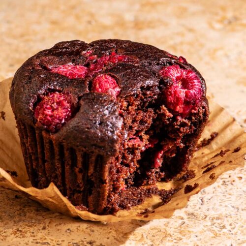 Close up of a chocolate muffin with raspberries.