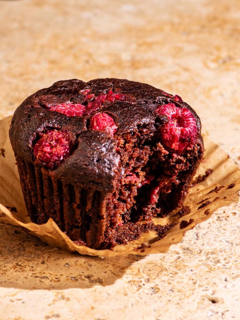 Close up of a chocolate muffin with raspberries.