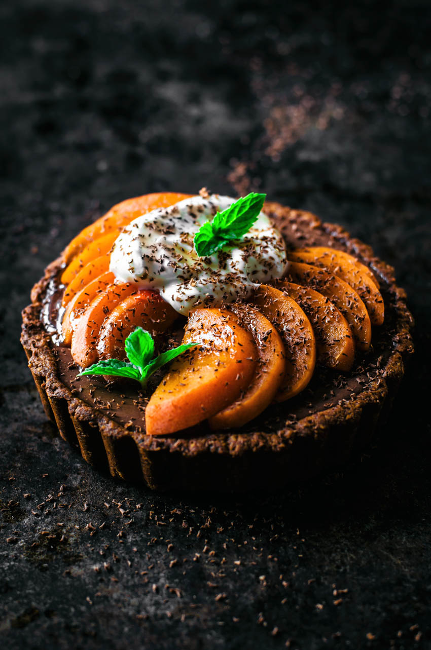 Front view of a tart with chocolate filling topped with apricot slices.