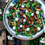 A big serving bowl with lamb's lettuce, blueberries, rhubarb, and croutons on a wooden crate.