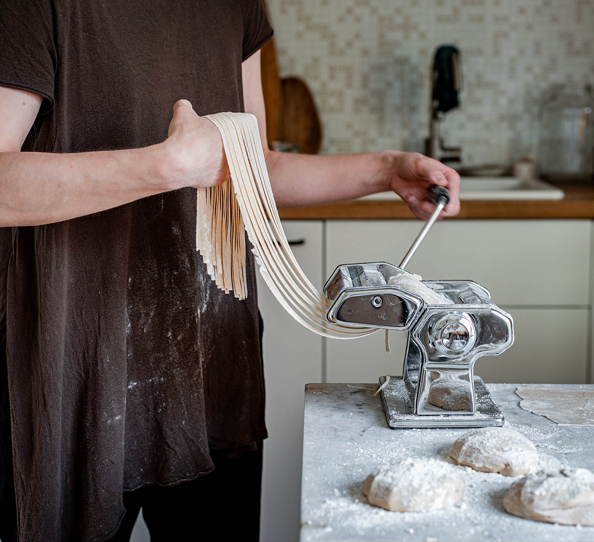 Woman lifting cut fettuccine from a pasta maker.