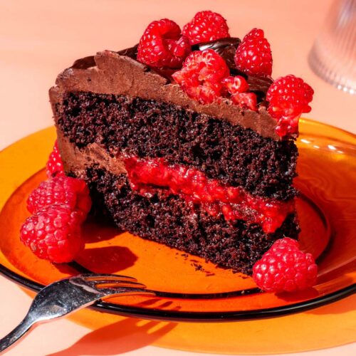 A slice of raspberry chocolate layer cake on a glass plate.
