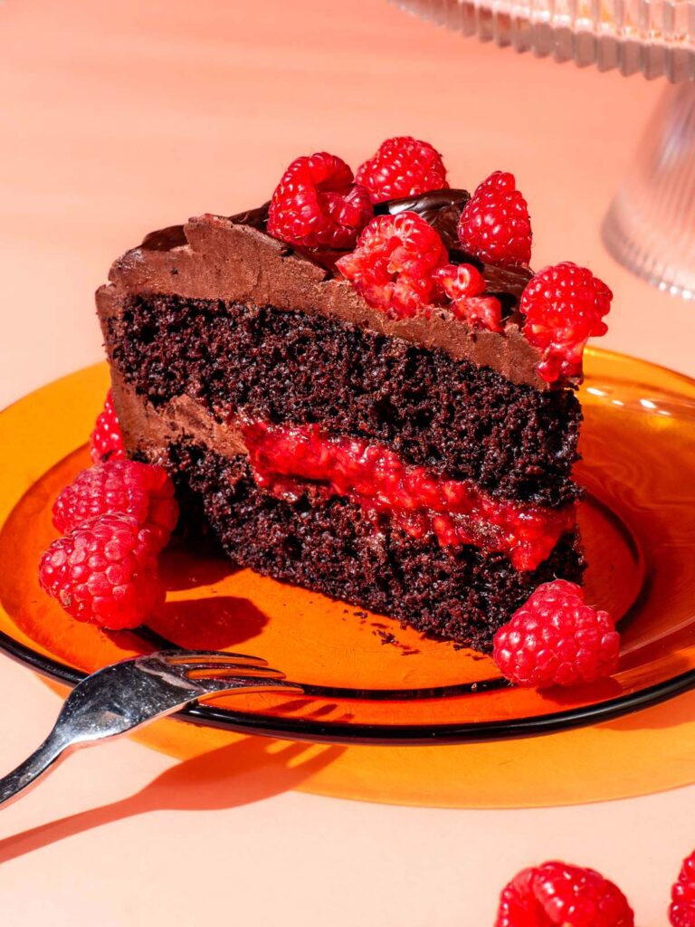 A slice of raspberry chocolate layer cake on a glass plate.
