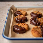Chocolate dipped peanut butter cookies on a tray.