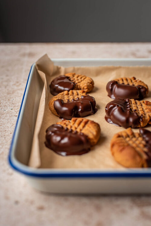 Chocolate dipped peanut butter cookies on a tray.