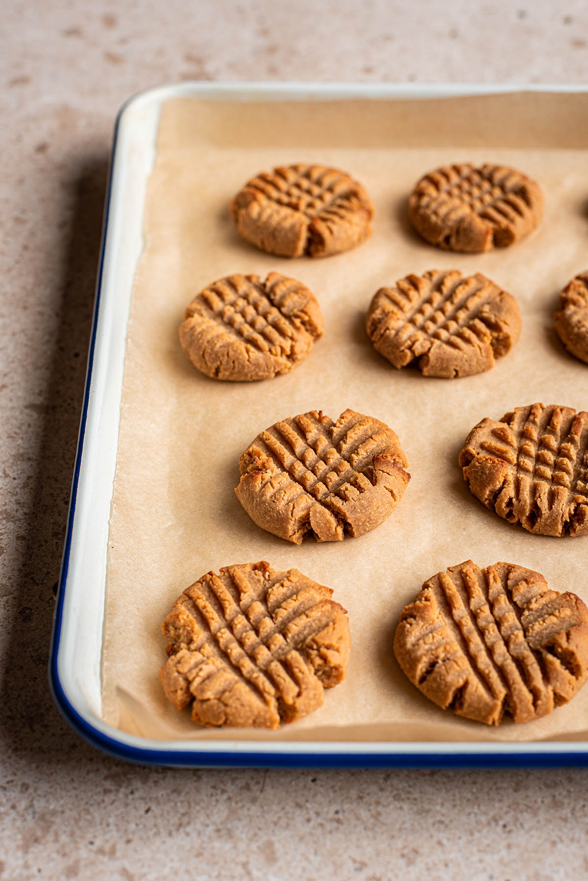 Baked cross-hatch gluten free peanut butter cookies on a tray.