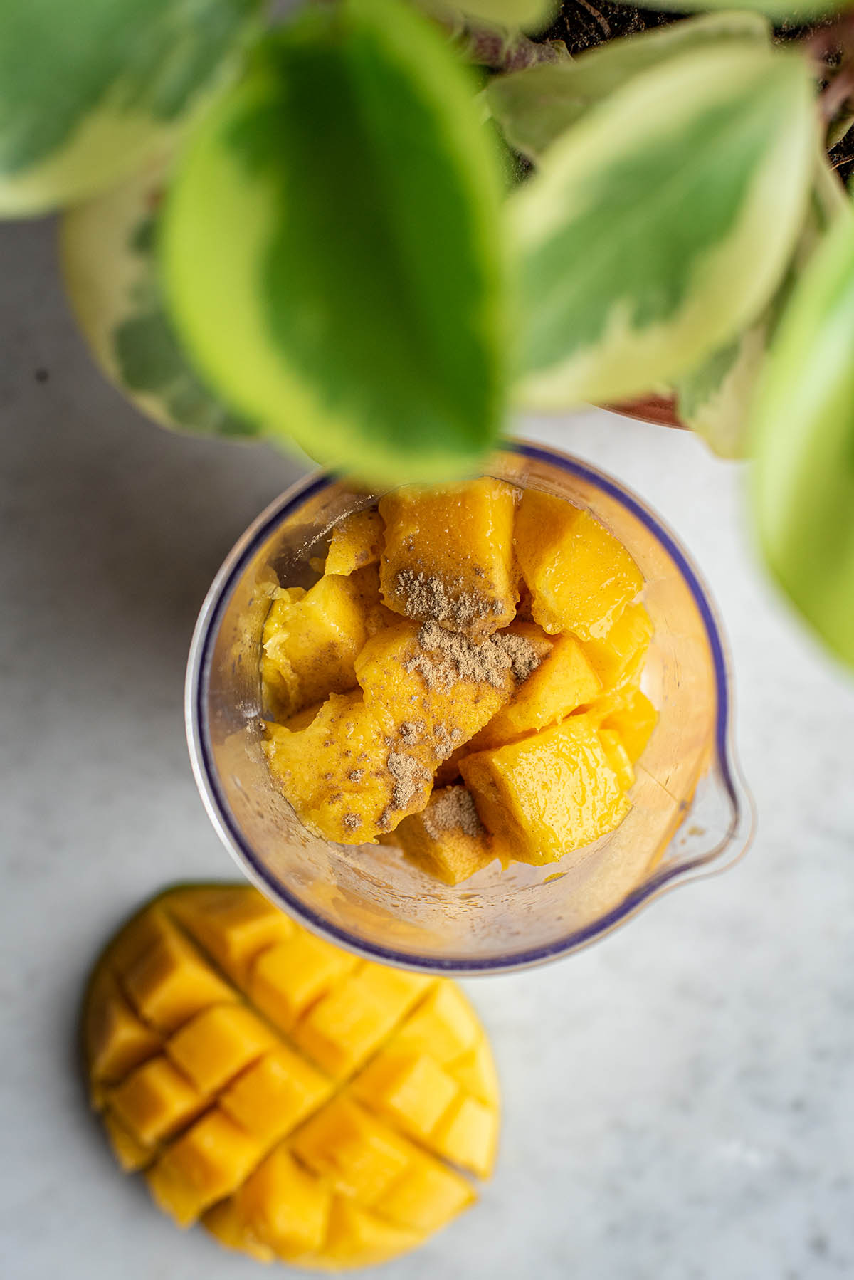 A mixing cup filled with fresh mango and cardamom.