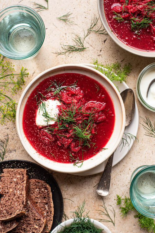 A bowl of red beet borscht topped with dill and yogurt.