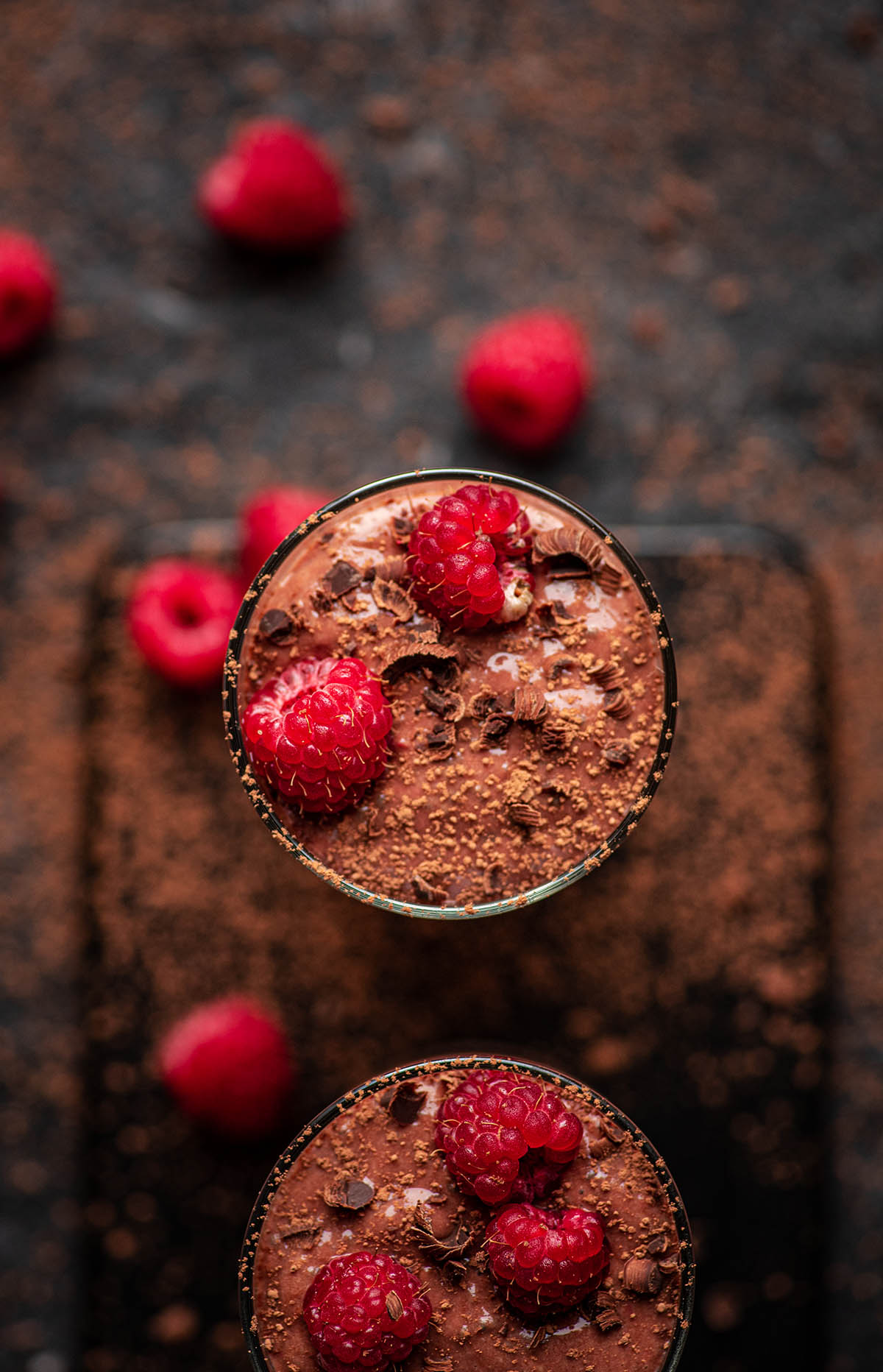 A chocolate protein shake in glasses with raspberries.