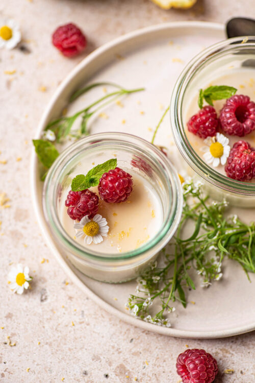 Two small glass jars filled with off-white pudding topped with berries.