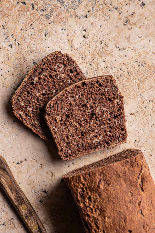 Two slices of dark rye bread with oats cut from a loaf.