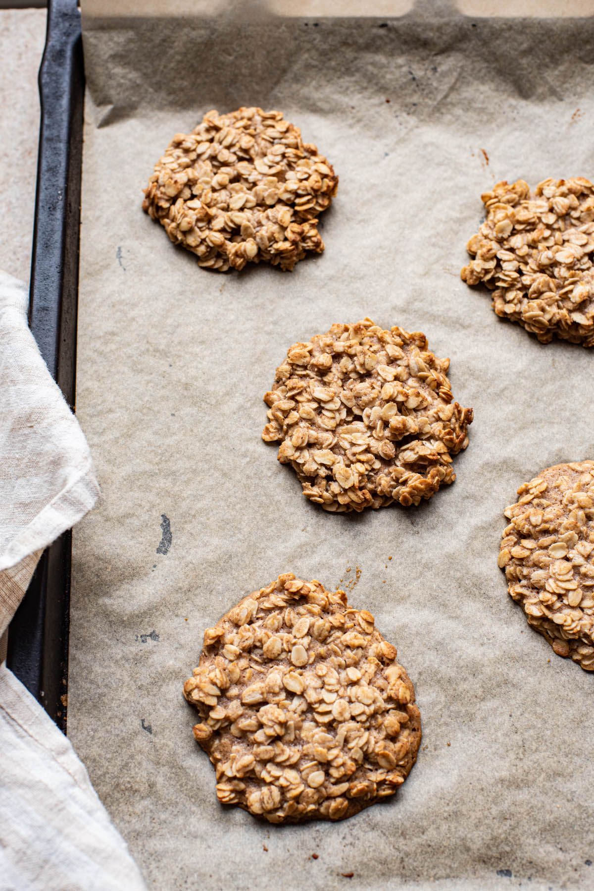 Baked thin oatmeal cookies on a baking sheet.