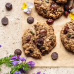 A cookie broken in half on a corner of parchment paper.