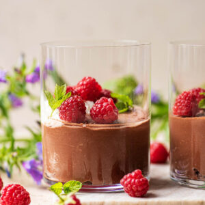 Vegan chocolate mousse in glasses with cream and raspberries.