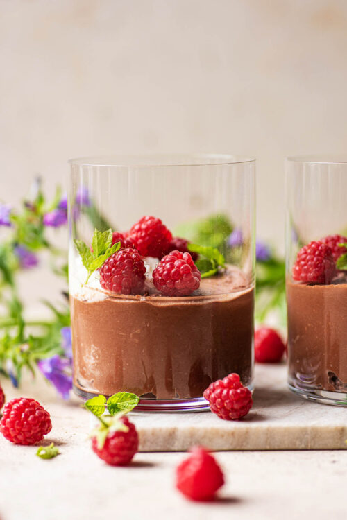 Vegan chocolate mousse in glasses with cream and raspberries.