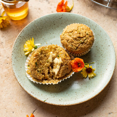Halved muffin on a green plate with flowers and another muffin.