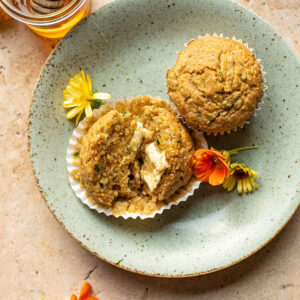 Halved muffin on a green plate with flowers and another muffin.