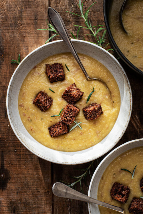 Close up of two bowls of soup on a warm wooden background.