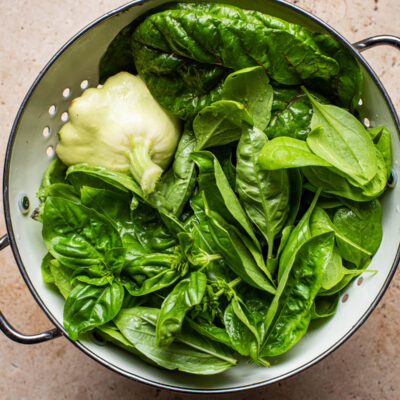 Zucchini, basil, and greens in a colander.