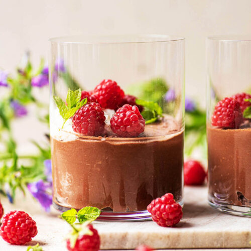 Vegan chocolate mousse in glasses with cream and raspberries.
