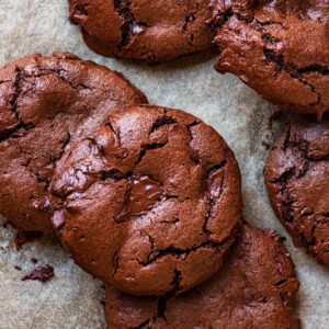 Chocolate cookies piled on a baking sheet.