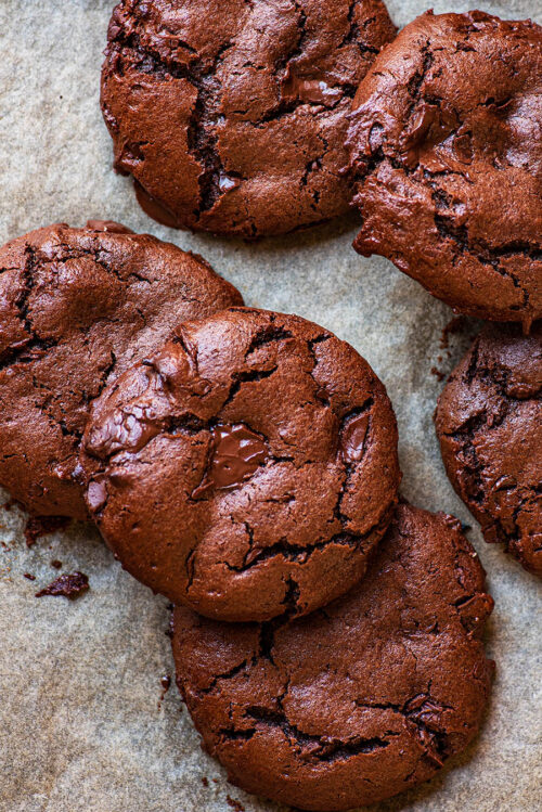 Chocolate cookies piled on a baking sheet.