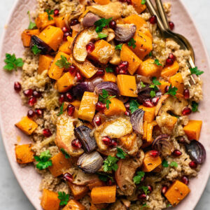 Moroccan spiced quinoa salad with butternut squash, red onion, and apples on pink platter.