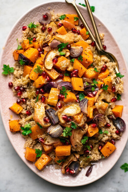 Moroccan spiced quinoa salad with butternut squash, red onion, and apples on pink platter.